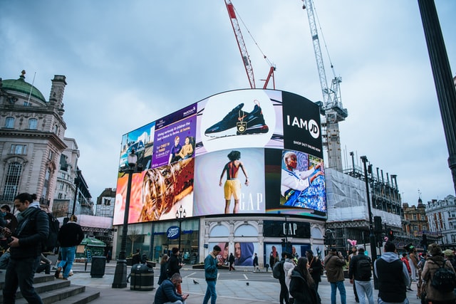 People walking in front of advertising billboards in London