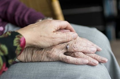 Woman placing hand over the hands of an older person.